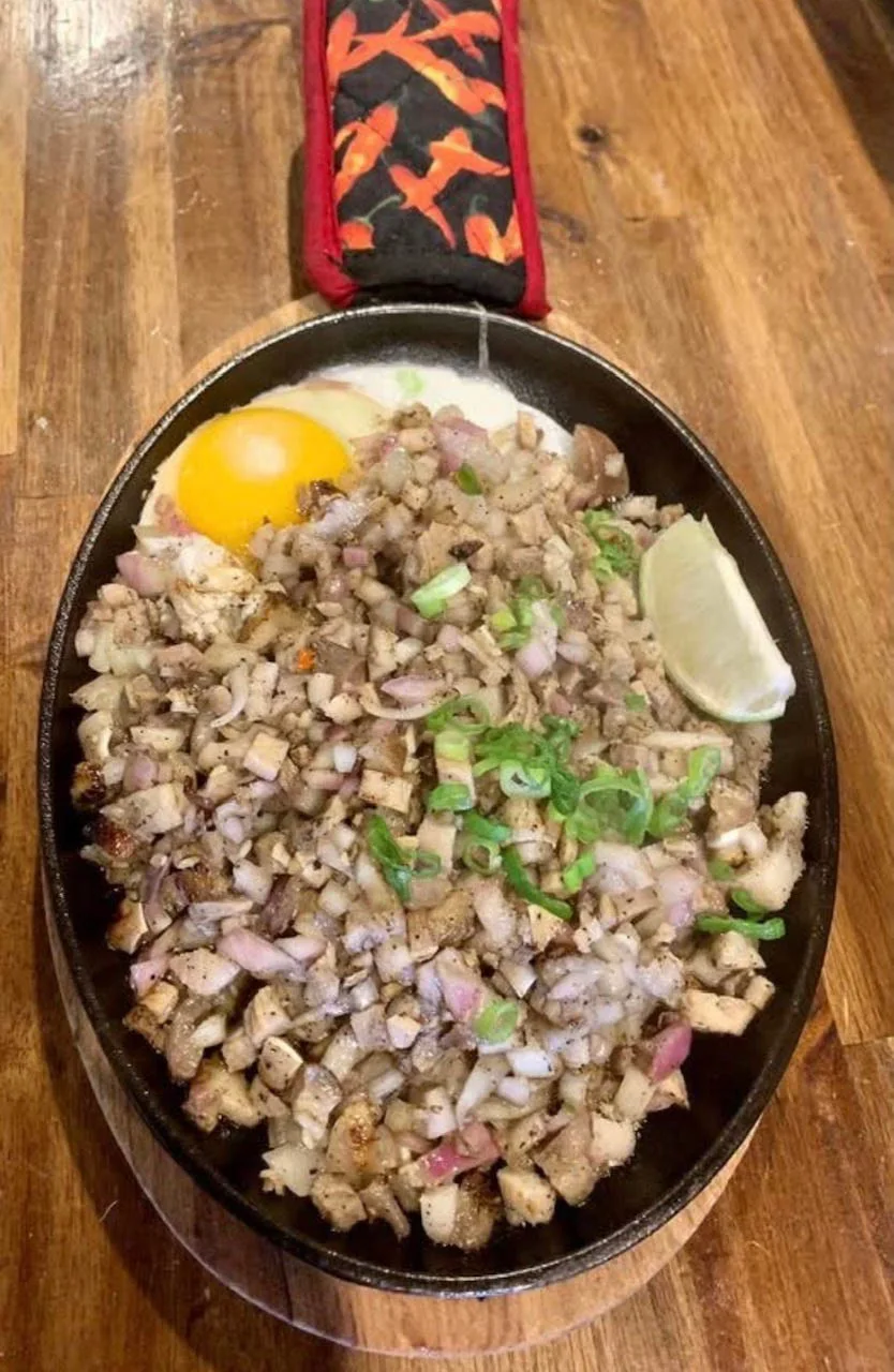 Pork sisig with a raw egg on a sizzling plate